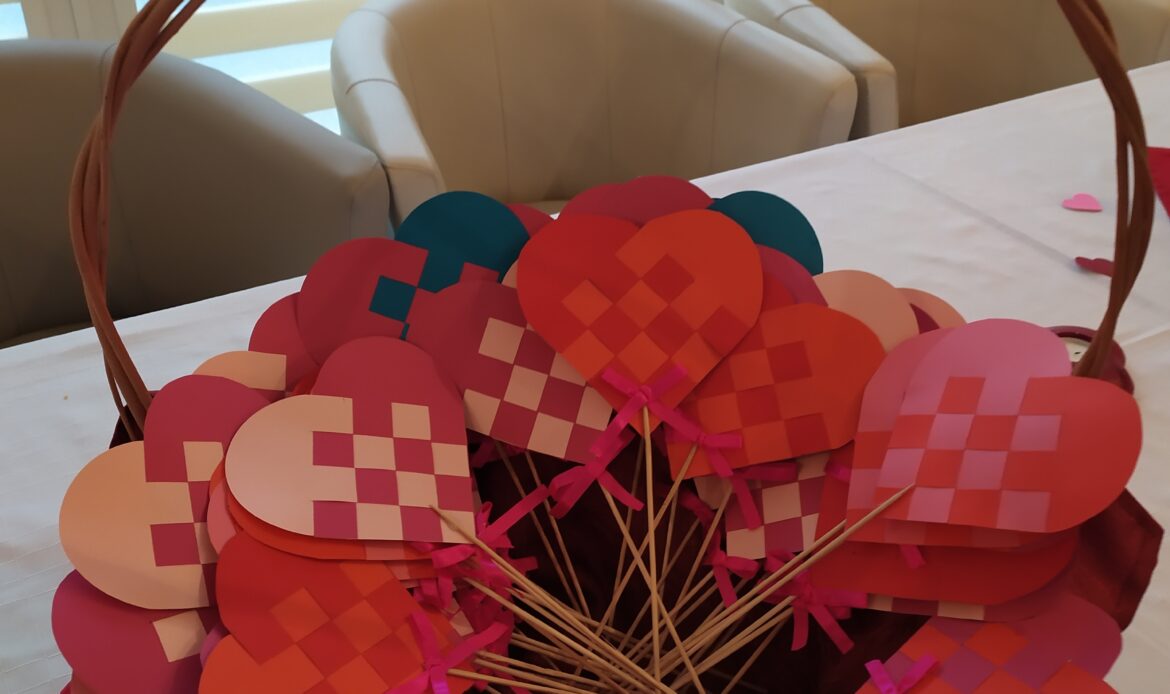 Wiklinowy koszyk z dwukolorowymi sercami na patykach, wykonanymi metodą przeplatania.