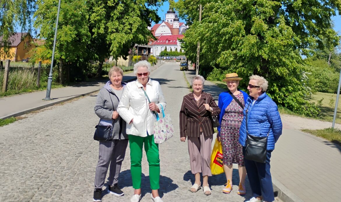 Pięć osób stoi na drodze, w tle drzewa i zabudowania klasztorne.