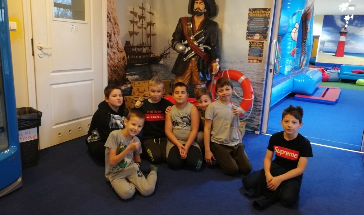 chłopcy pozują przed piratem w sali zabaw