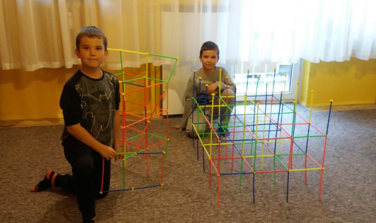 Chłopcy tworzą budowle z plastikowych rurek