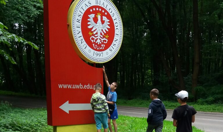 Dzieci przed kierunkowskazem wskazującym Uniwersytet w Białymstoku