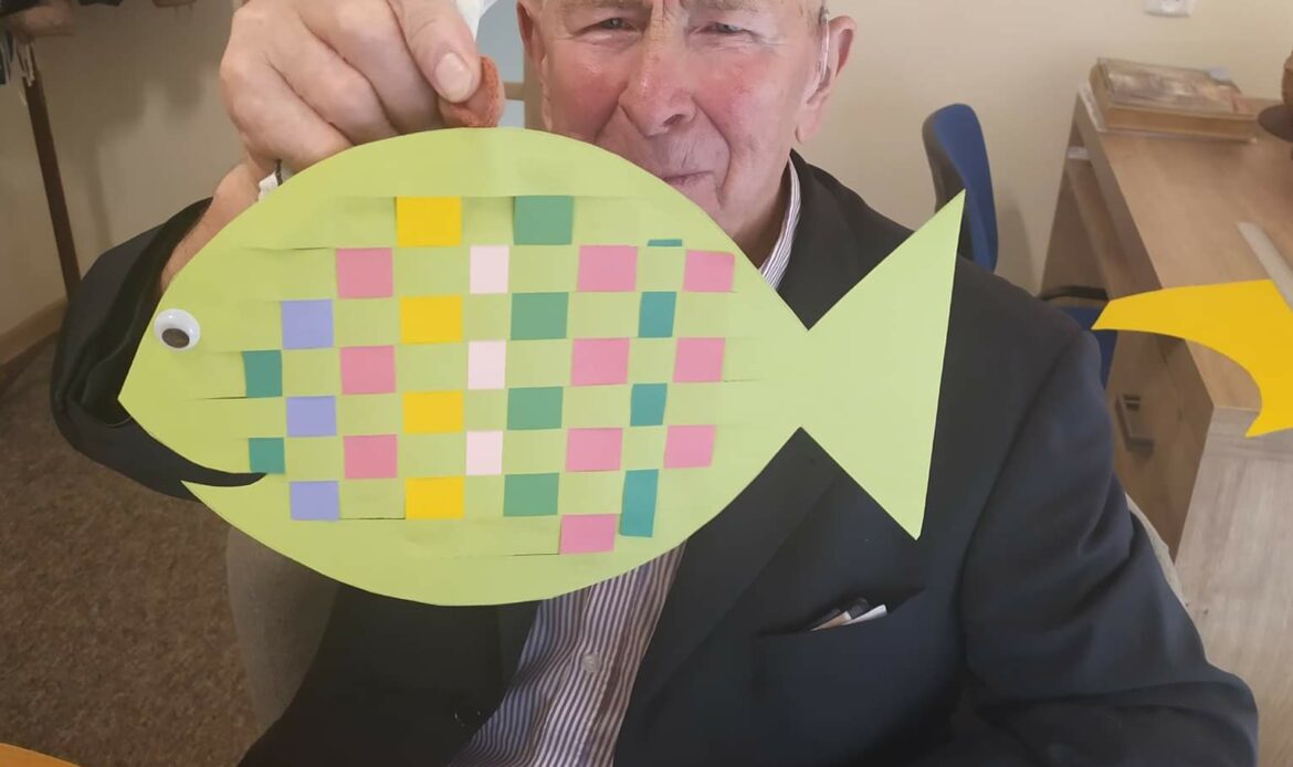 Pan pokazuje własnoręcznie zrobioną rybkę z papieru