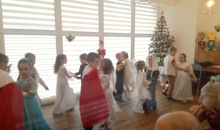 Dzieci w przebraniach wykonują taniec w parach, dziewczynki tańczą z chłopcami.