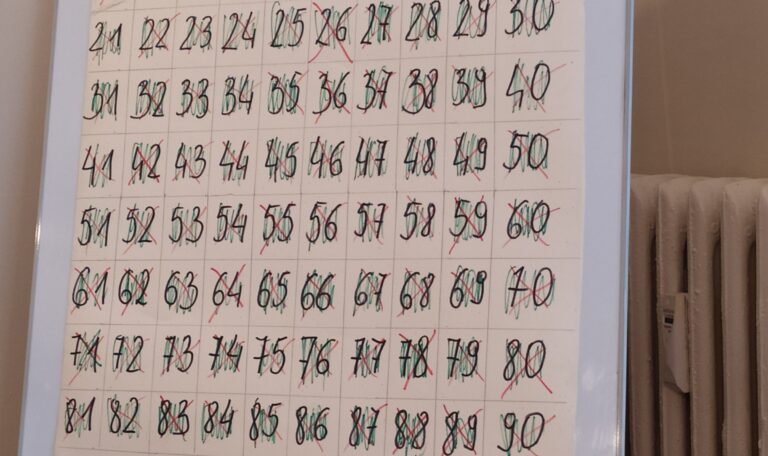 Tablica ze skreślonymi liczbami od 21 do 90 zapisanymi w tabeli.