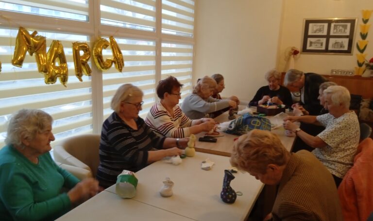 Grupa seniorek siedzi przy stole i formuje zajączki ze skarpetek.